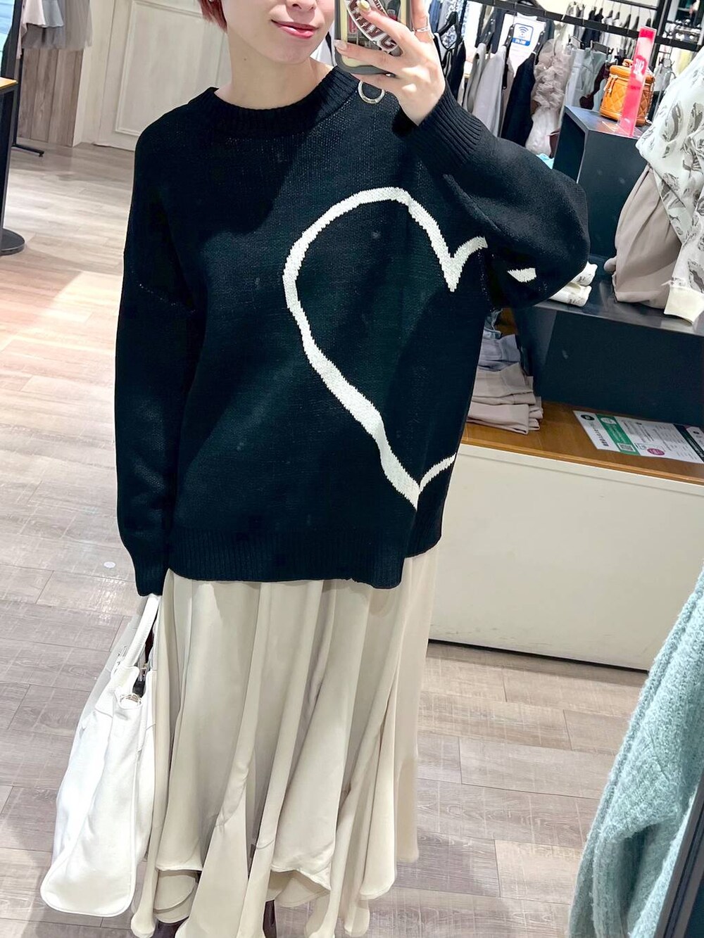 ホワイト系のトートバッグ、ブラウン系のブーツ、ベージュ系のスカートを着用したレディースの冬コーディネートの4枚目の写真