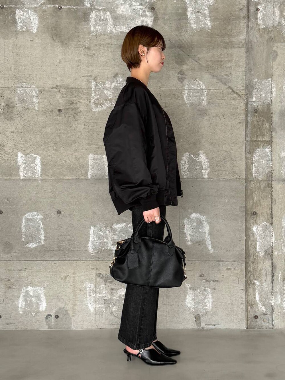 ブラック系のボストンバッグ、ブラック系のデニムパンツ、ブラック系のサンダルを着用したレディースの冬コーディネートの2枚目の写真