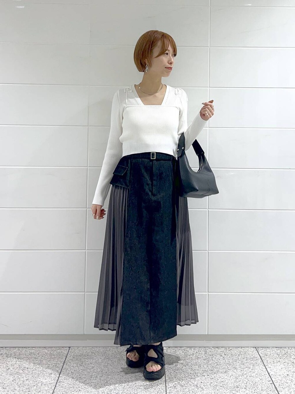 ブラック系のスカート、ホワイト系のカーディガン/ボレロ、ブラック系のサンダルを着用したレディースの春コーディネートの2枚目の写真