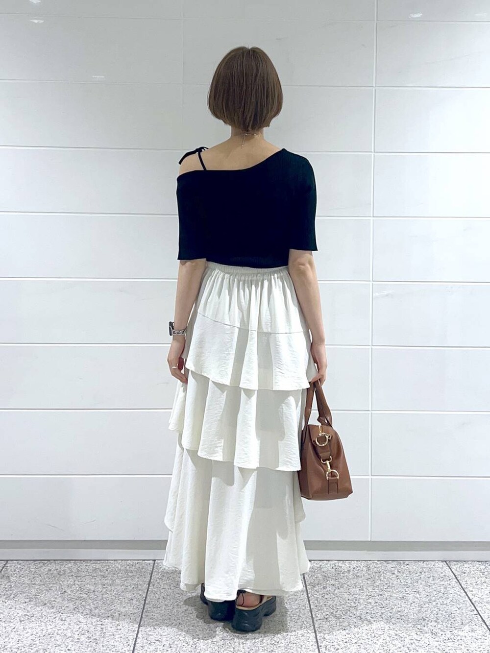 ホワイト系のスカート、ベージュ系のサンダル、ブラック系のニット/セーターを着用したレディースの春コーディネートの3枚目の写真