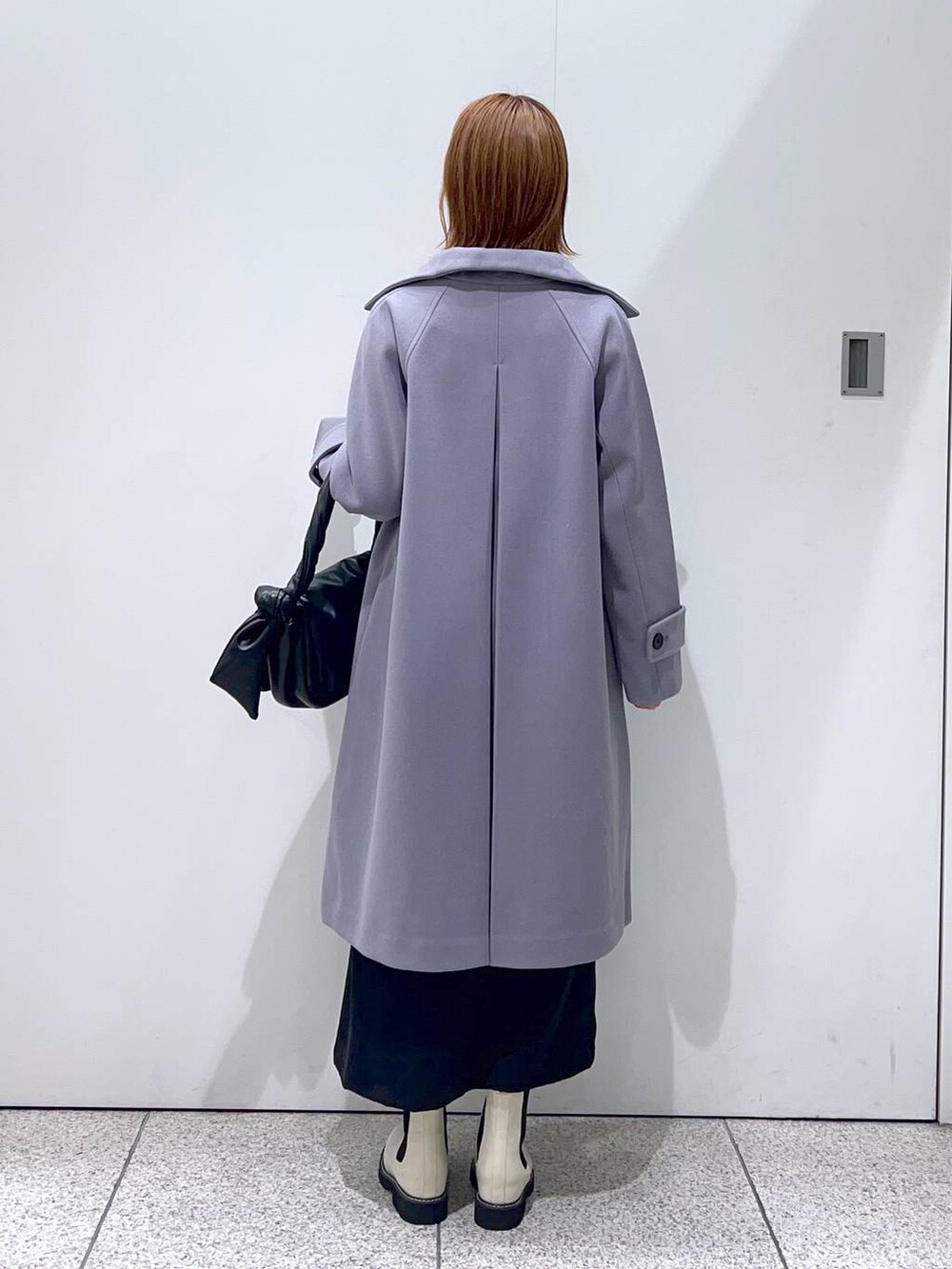 グレー系のチェスターコート、ホワイト系のブーツ、ホワイト系のニット/セーターを着用したレディースの秋コーディネートの3枚目の写真