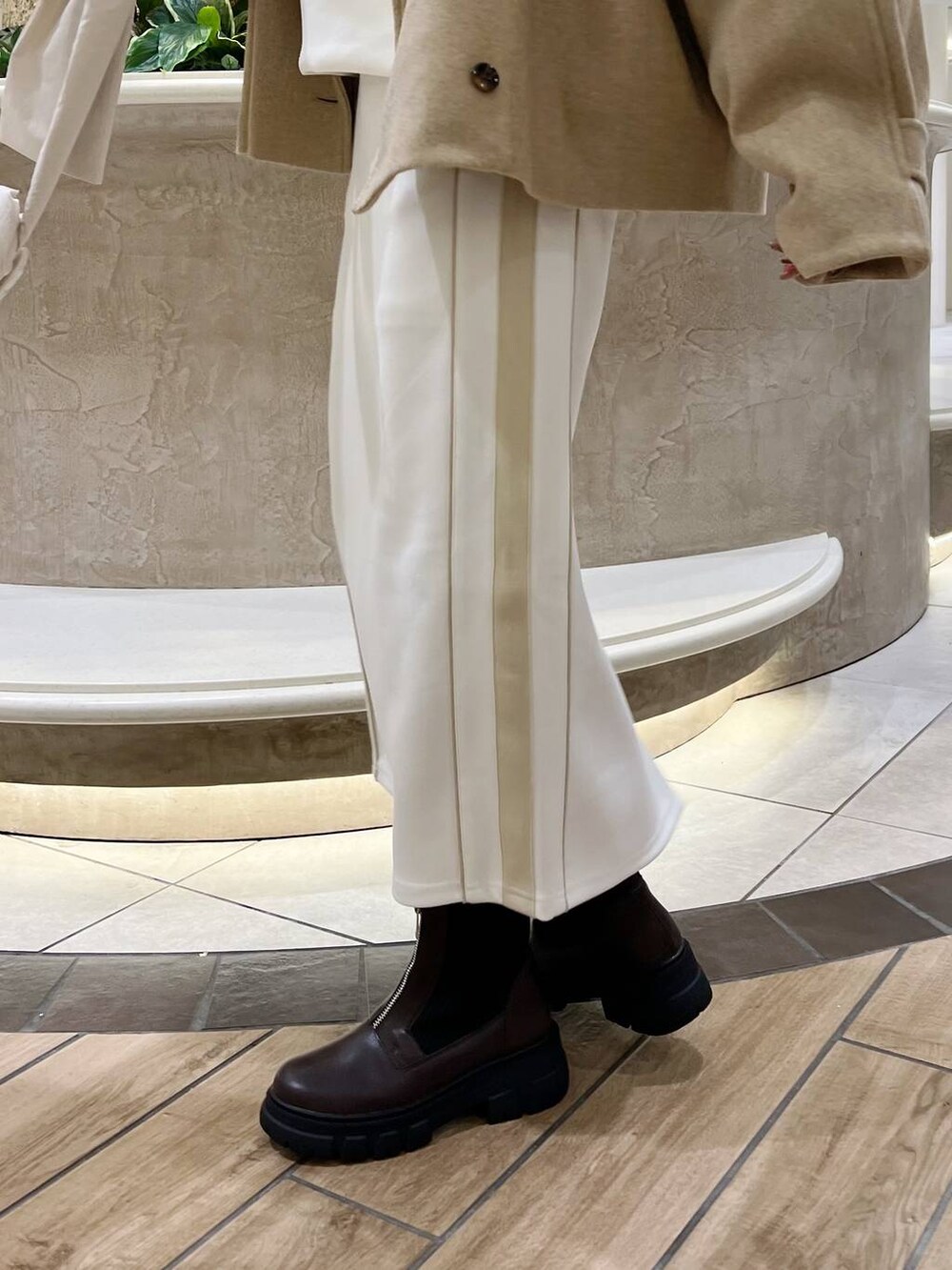 ベージュ系のピーコート、ホワイト系のショルダーバッグ、ブラウン系のブーツを着用したレディースの秋コーディネートの7枚目の写真