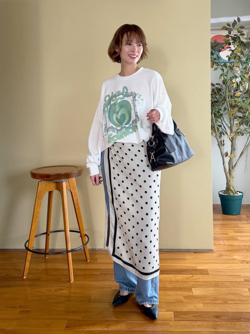 ブラック系のボストンバッグ、ブルー系のデニムパンツ、ブラック系のパンプスを着用したレディースの春コーディネートの5枚目の写真