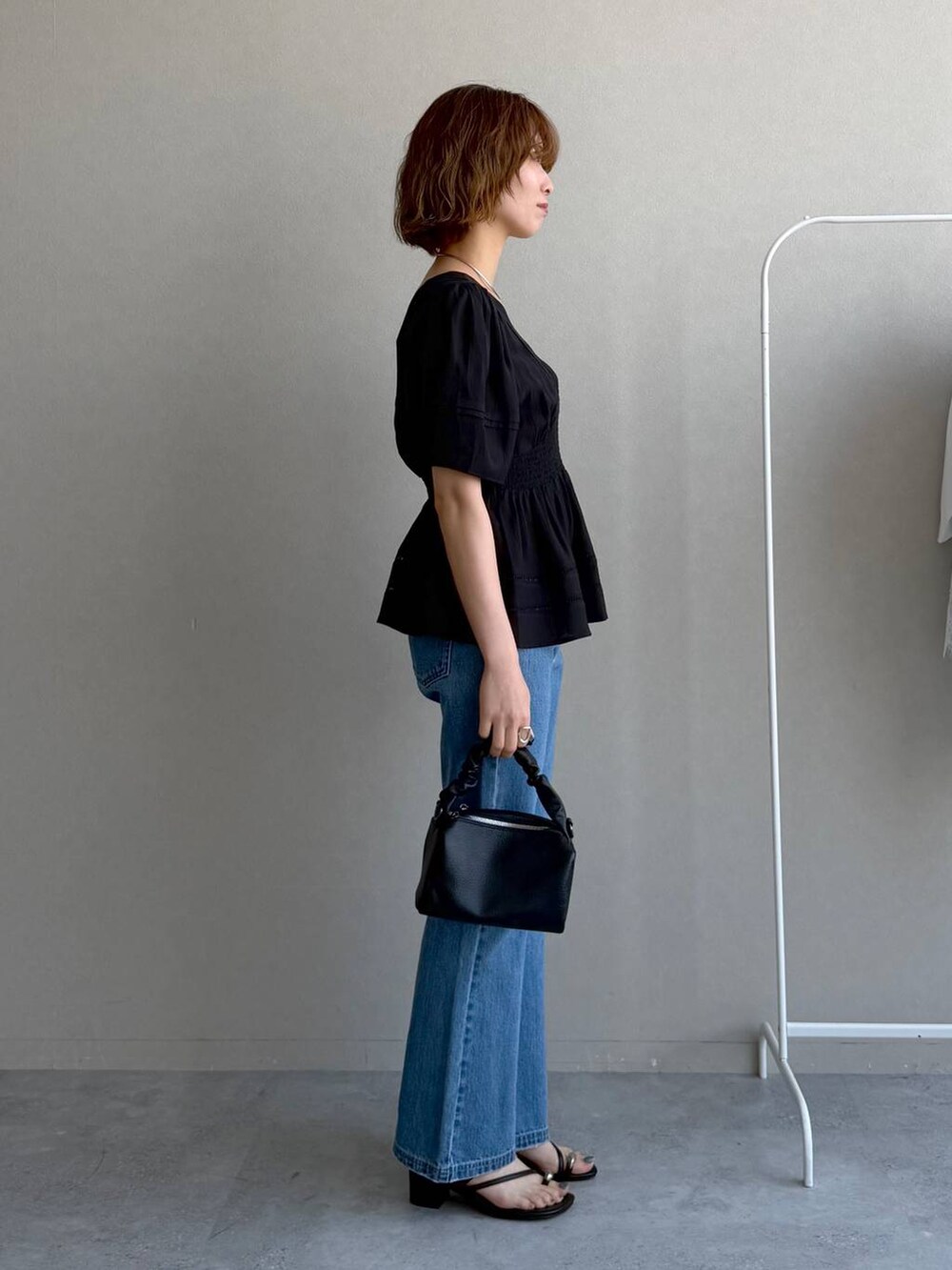 ブルー系のデニムパンツ、ブラック系のキャミソール、ブラック系のショルダーバッグを着用したレディースの春コーディネートの2枚目の写真