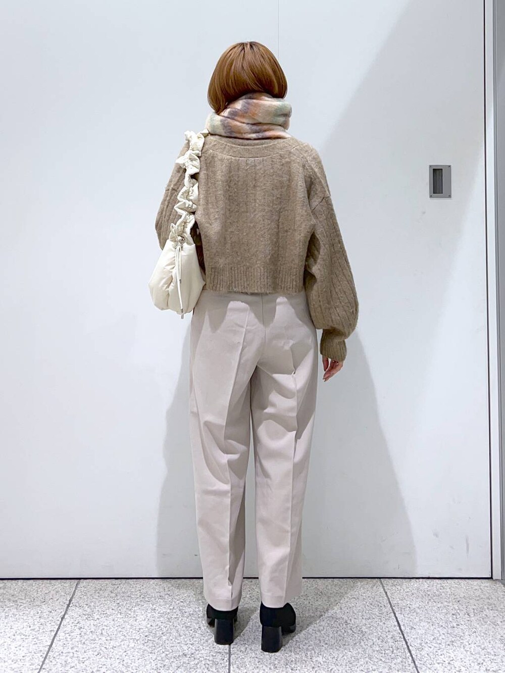 ホワイト系のハンドバッグ、ブラック系のブーツ、ホワイト系のその他パンツを着用したレディースの秋コーディネートの3枚目の写真