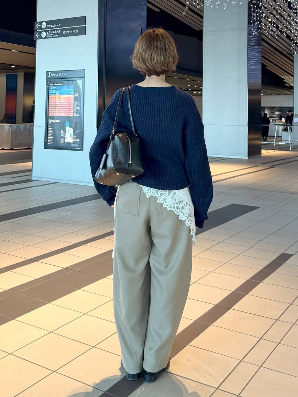 ブラック系のハンドバッグ、ブラック系のローファー、ブルー系のニット/セーターを着用したレディースの冬コーディネートの3枚目の写真