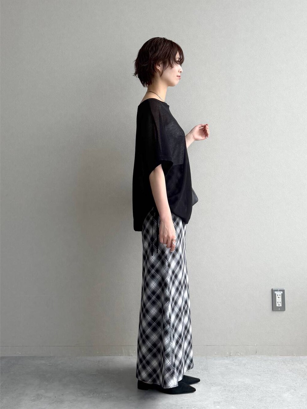 ブラック系のサンダル、グレー系のスカート、ブラック系のショルダーバッグを着用したレディースの夏コーディネートの2枚目の写真