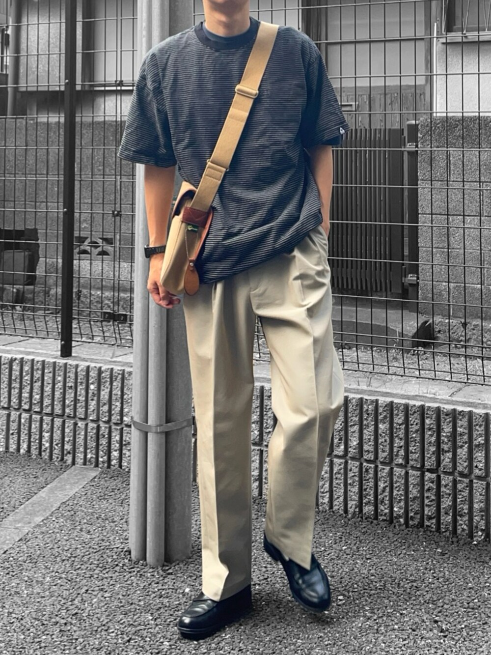 ブラック系のTシャツ/カットソー、ベージュ系のショルダーバッグ、ベージュ系のスラックスを着用したメンズの夏コーディネートの2枚目の写真