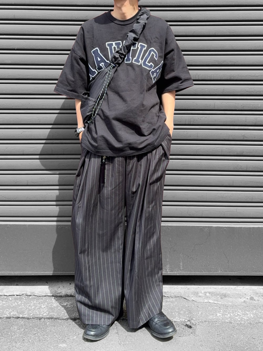 ブラック系のショルダーバッグ、ブラック系のスラックス、ブラック系のローファーを着用したメンズの夏コーディネートの3枚目の写真