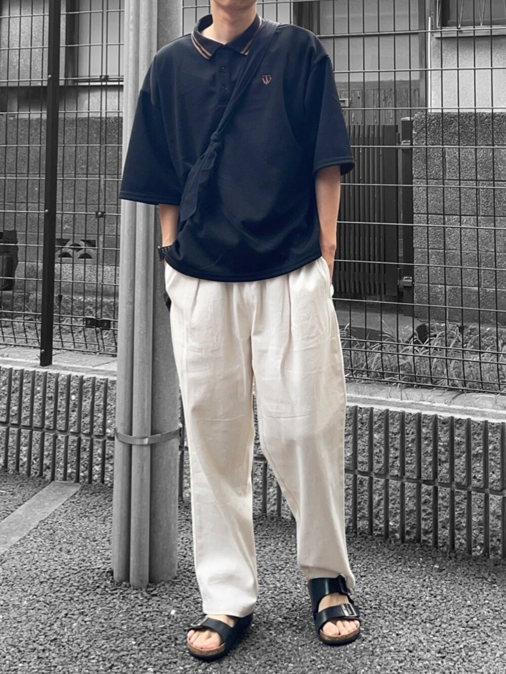 ブラック系のポロシャツ、ブラック系のショルダーバッグ、ホワイト系のその他パンツを着用したメンズの夏コーディネートの2枚目の写真