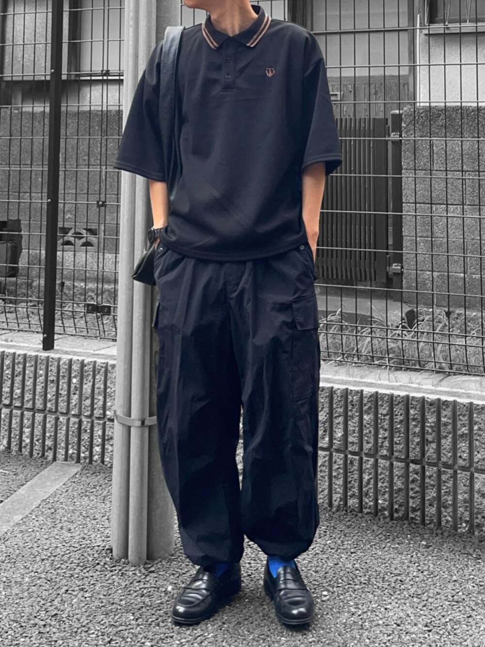 ブラック系のポロシャツ、ブラック系のトートバッグ、ブラック系のカーゴパンツを着用したメンズの夏コーディネートの2枚目の写真