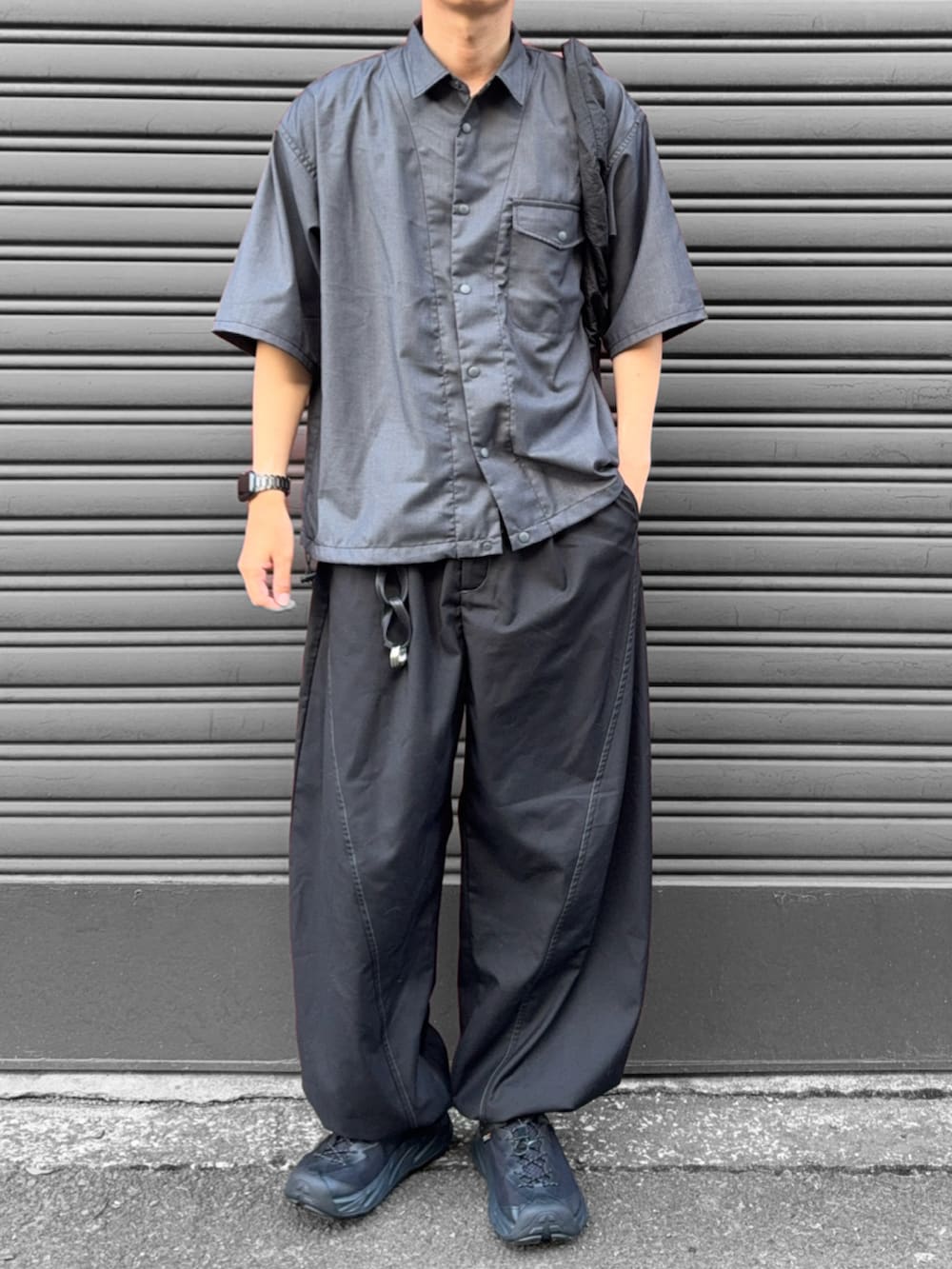 グレー系のシャツ/ブラウス、ブラック系のスラックス、ブラック系のショルダーバッグを着用したメンズの夏コーディネートの3枚目の写真