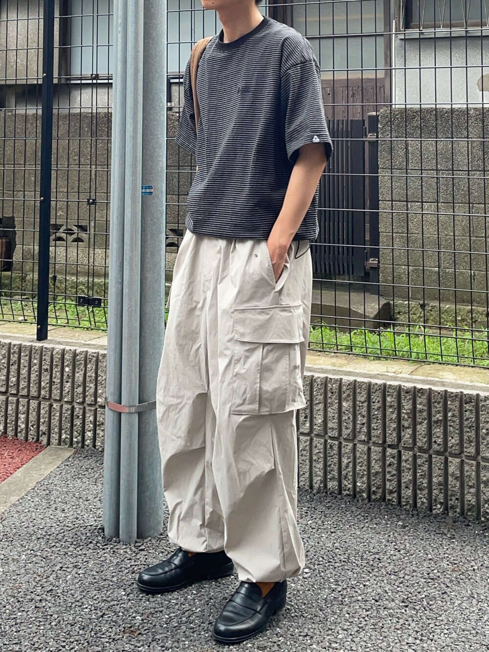 ブラック系のTシャツ/カットソー、ブラウン系のバッグ、グレー系のカーゴパンツを着用したメンズの夏コーディネートの2枚目の写真