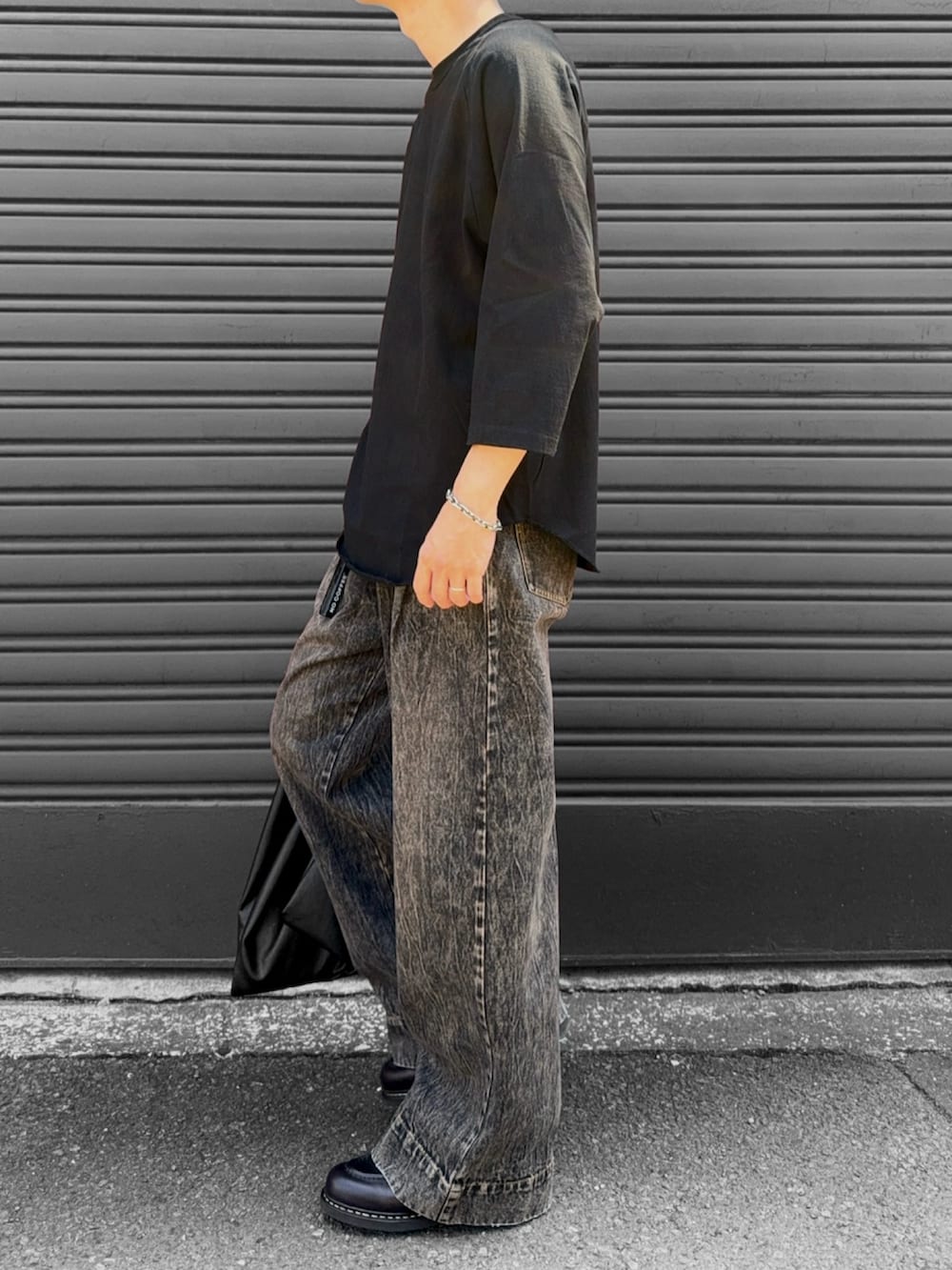 ブラウン系のモカシン/デッキシューズ、ブラック系のトートバッグ、ブラック系のデニムパンツを着用したメンズの秋コーディネートの3枚目の写真