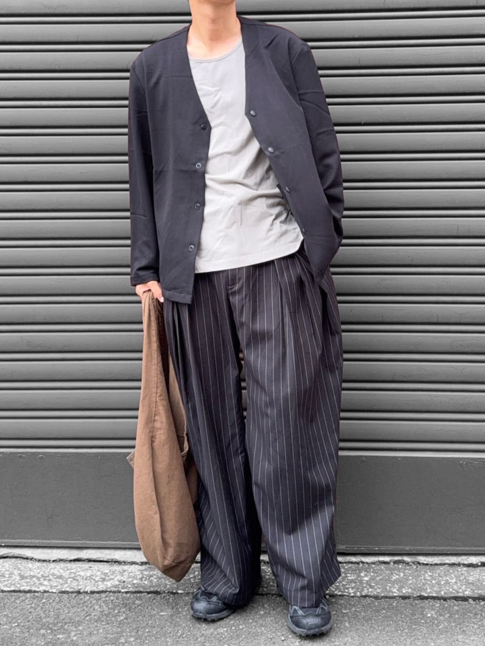 グレー系のタンクトップ、ブラック系のカーディガン/ボレロ、ブラック系のスラックスを着用したメンズの秋コーディネートの2枚目の写真