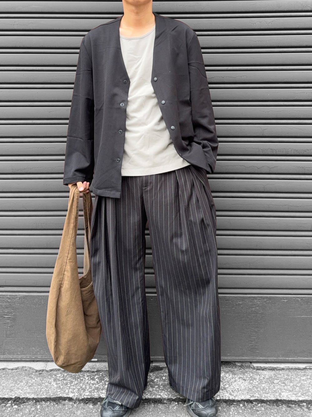 グレー系のタンクトップ、ブラック系のカーディガン/ボレロ、ブラック系のスラックスを着用したメンズの秋コーディネートの3枚目の写真