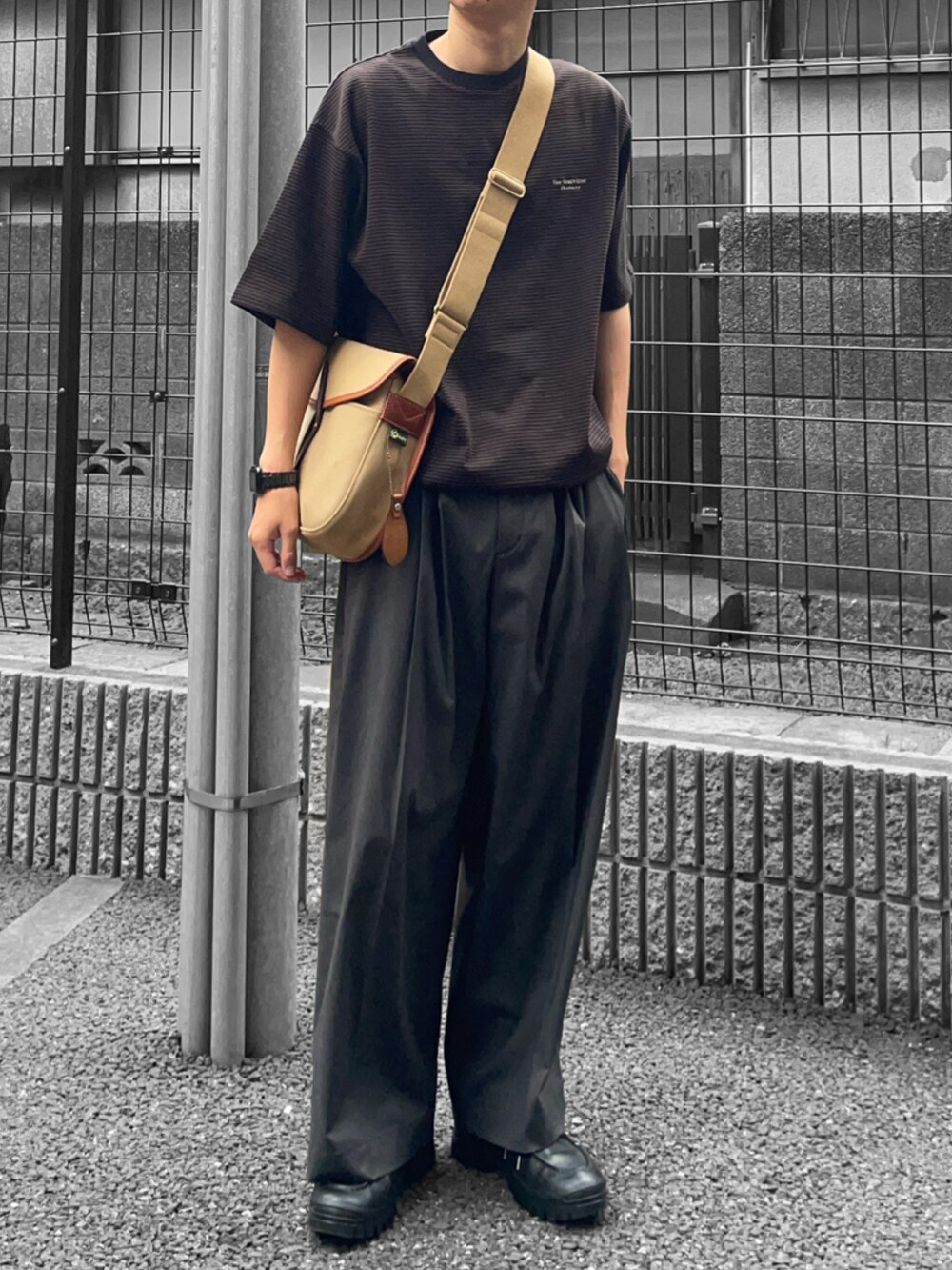 ブラウン系のTシャツ/カットソー、ベージュ系のショルダーバッグ、グレー系のスラックスを着用したメンズの夏コーディネートの2枚目の写真