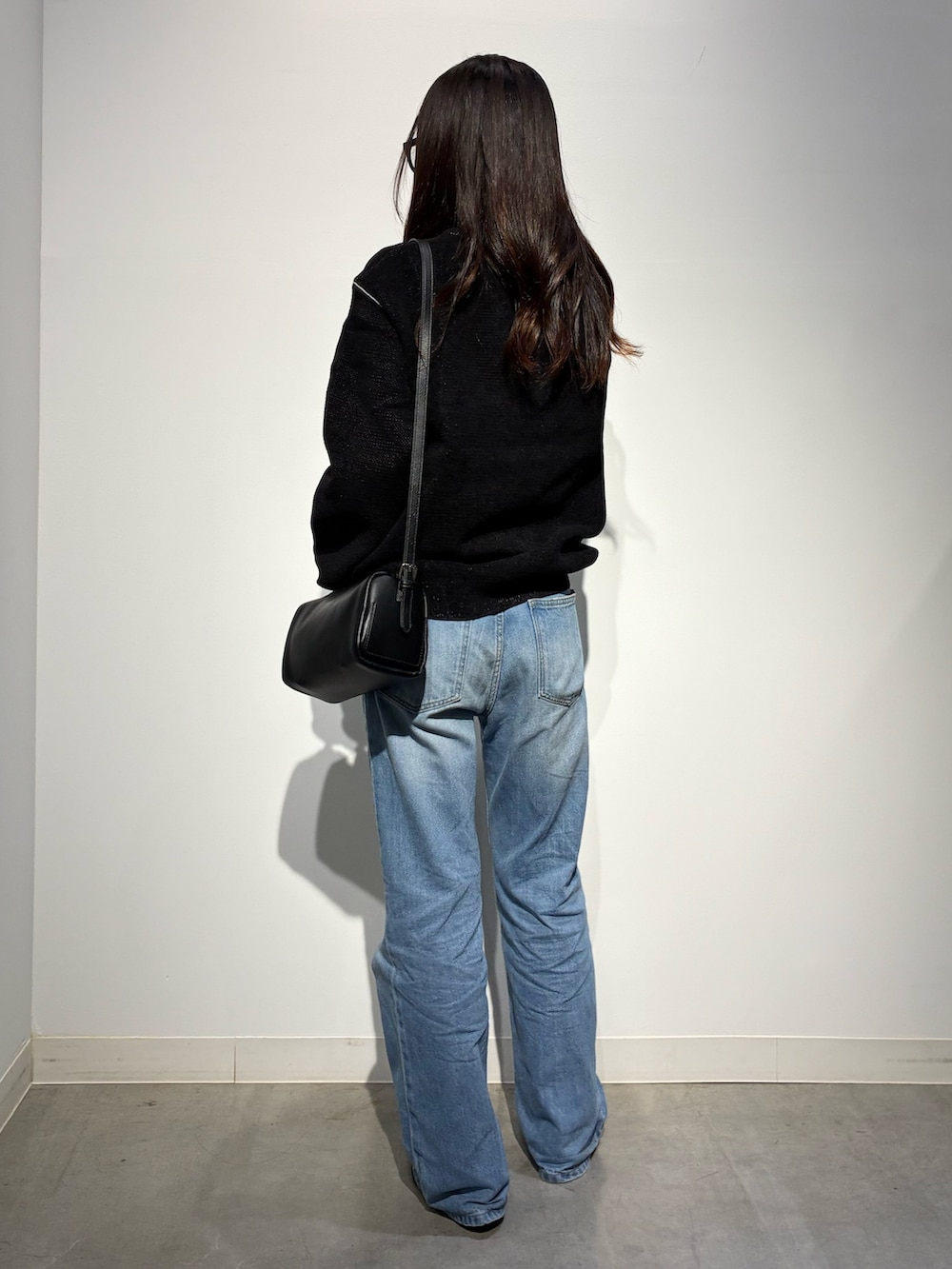 ブラック系のパンプス、ブルー系のデニムパンツ、ブラウン系のショルダーバッグを着用したレディースの秋コーディネートの3枚目の写真