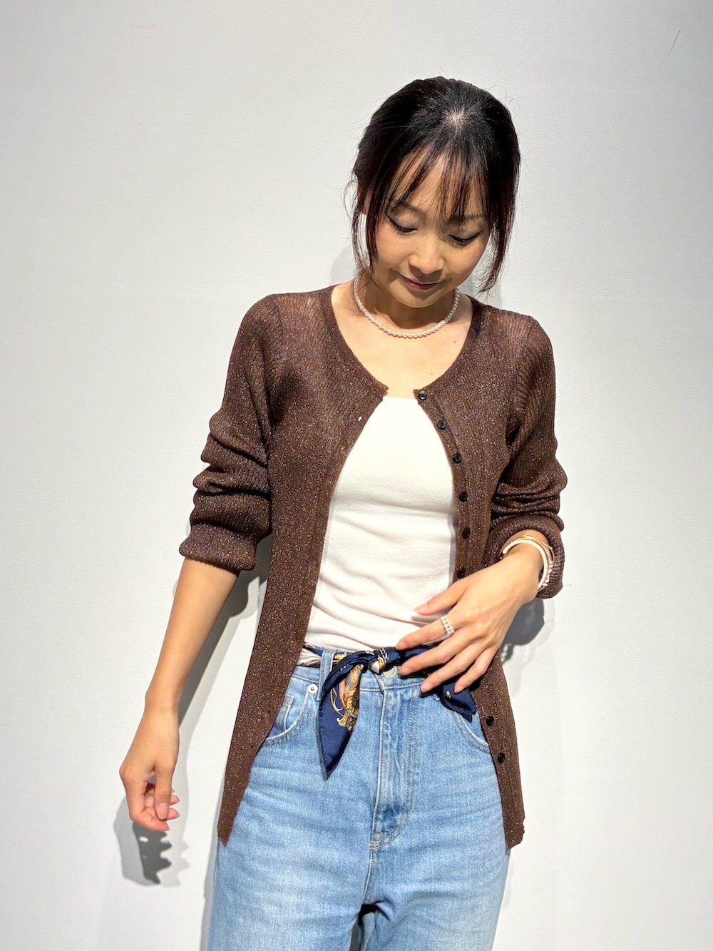 ブラウン系のニット/セーター、ホワイト系のTシャツ/カットソー、ブラウン系のショルダーバッグを着用したレディースの夏コーディネートの2枚目の写真
