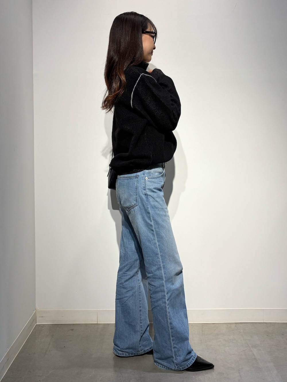 ブラック系のパンプス、ブルー系のデニムパンツ、ブラウン系のショルダーバッグを着用したレディースの秋コーディネートの2枚目の写真