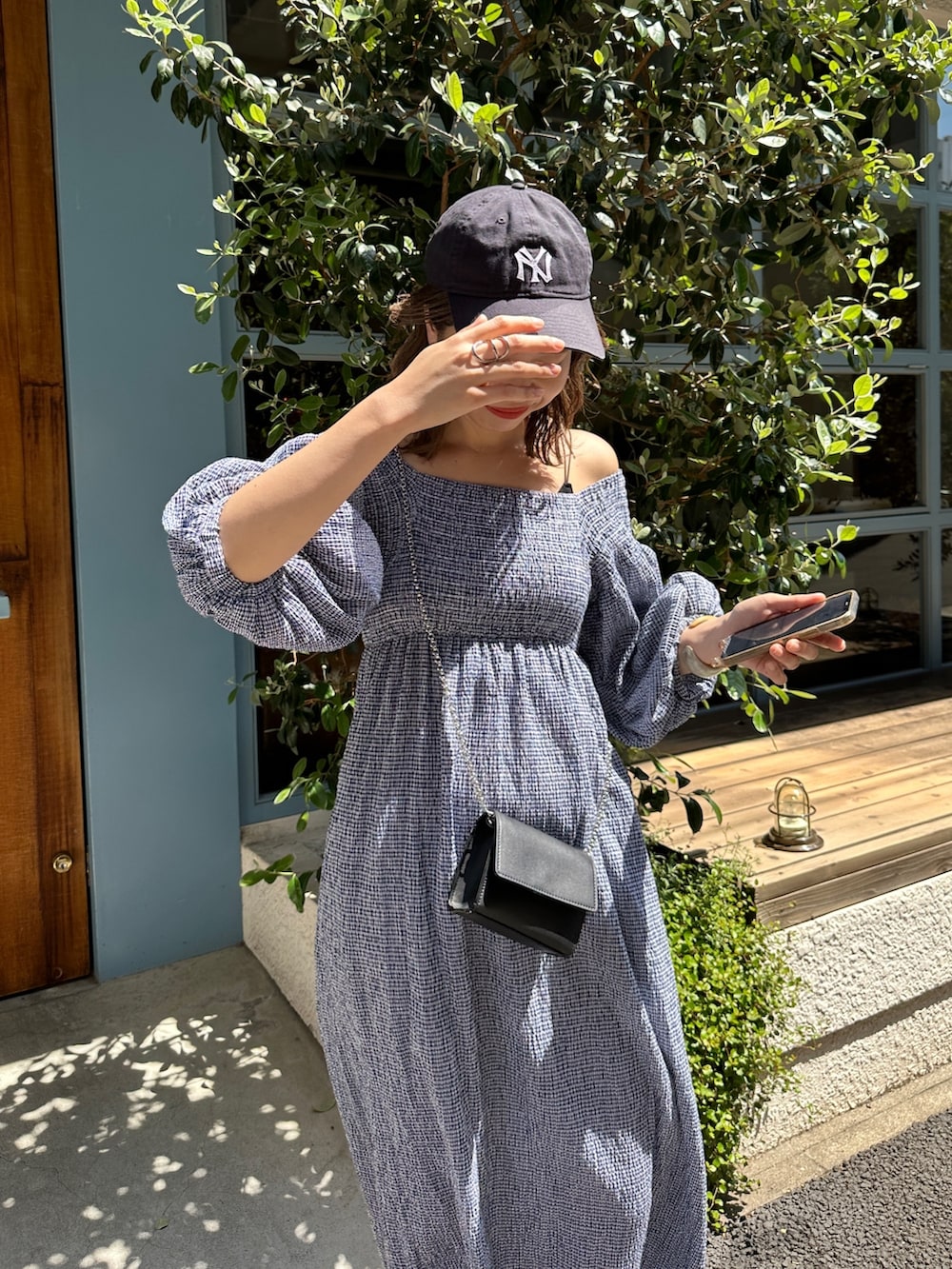 「夏コーデ、大人カジュアル、初夏コーデ、ミニバッグ、高身長コーデ、キャップ、ニューエラ、ワンポイント、ワンピース、ギンガムチェック、オフショル、スニーカーコーデ、チェック、ショルダーバッグ、Kastane」｜「Kastaneの【WEB限定/サイズ展開あり】ギンガムシャーリングワンピース（ワンピース、ブルー系）」を使った、かとまりさん（レディース・166cm）の春コーディネートの2枚目の写真