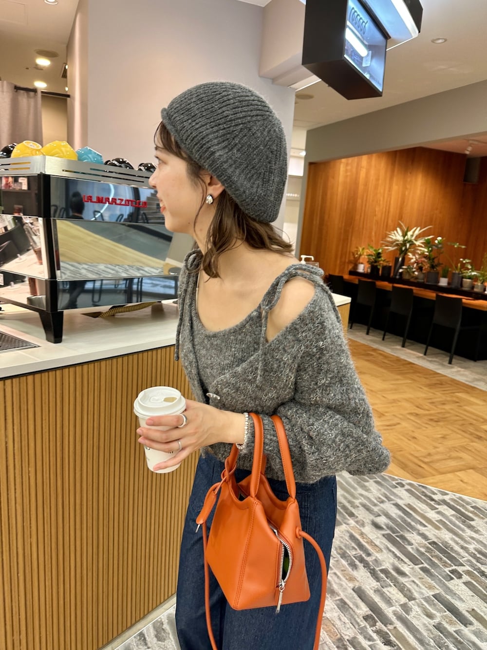 グレー系のトップス、オレンジ系のトートバッグ、ブルー系のデニムパンツを着用したレディースの夏コーディネートの3枚目の写真