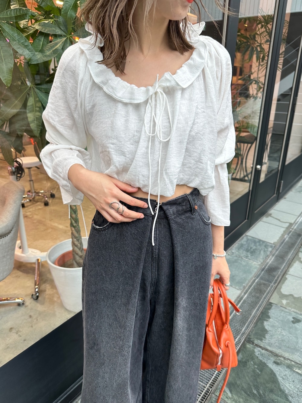 ブラック系のデニムパンツ、ホワイト系のシャツ/ブラウス、オレンジ系のトートバッグを着用したレディースの夏コーディネートの3枚目の写真