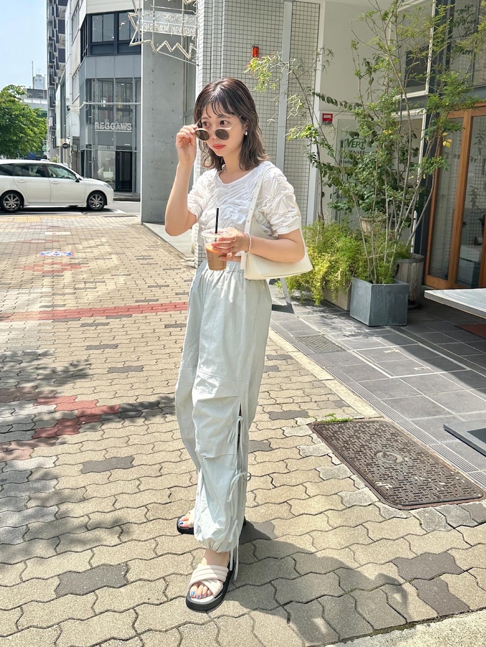 グリーン系のカーゴパンツ、ホワイト系のTシャツ/カットソー、ブラック系のサンダルを着用したレディースの春コーディネートの2枚目の写真