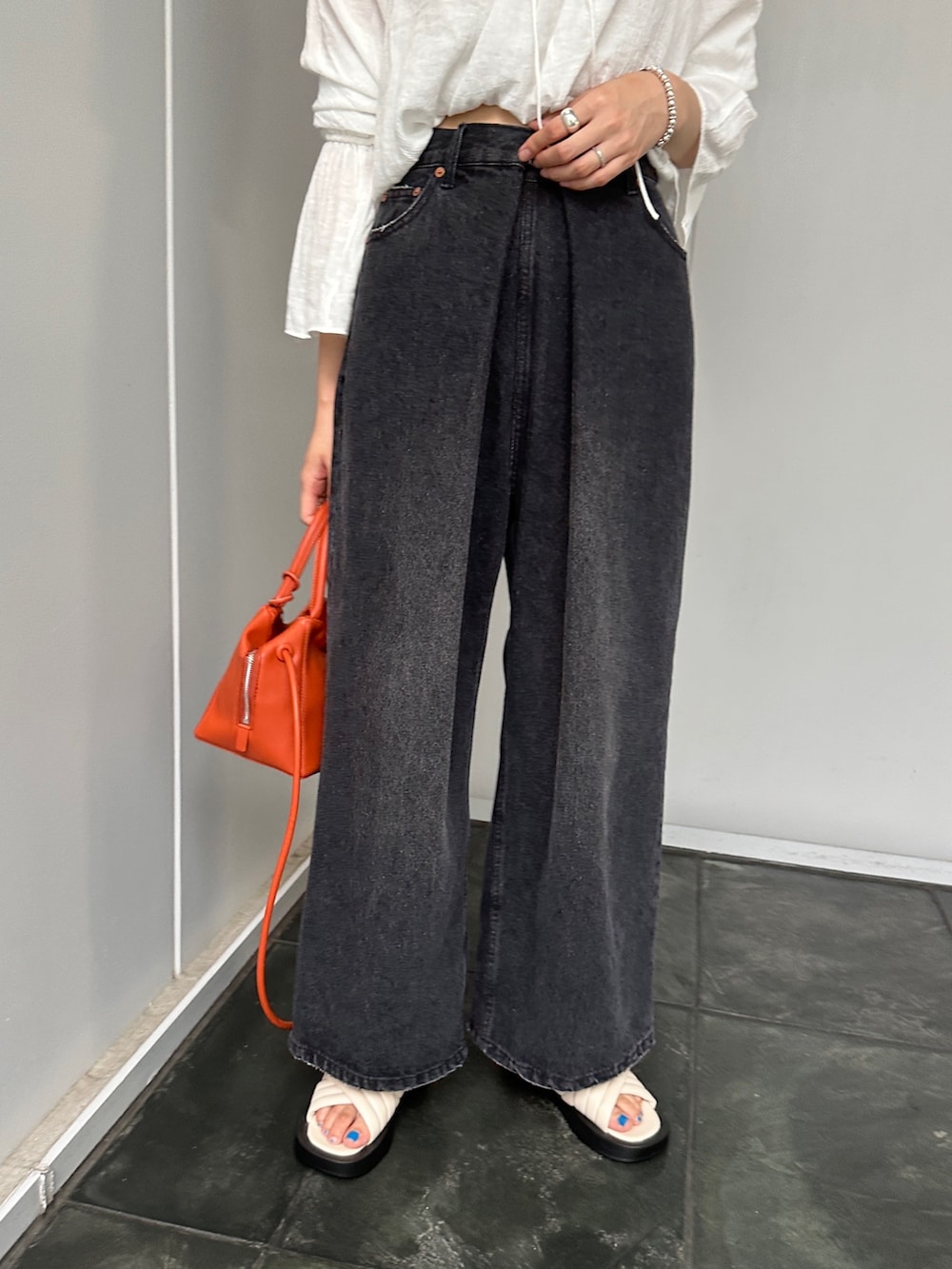 ブラック系のデニムパンツ、ホワイト系のシャツ/ブラウス、オレンジ系のトートバッグを着用したレディースの夏コーディネートの4枚目の写真