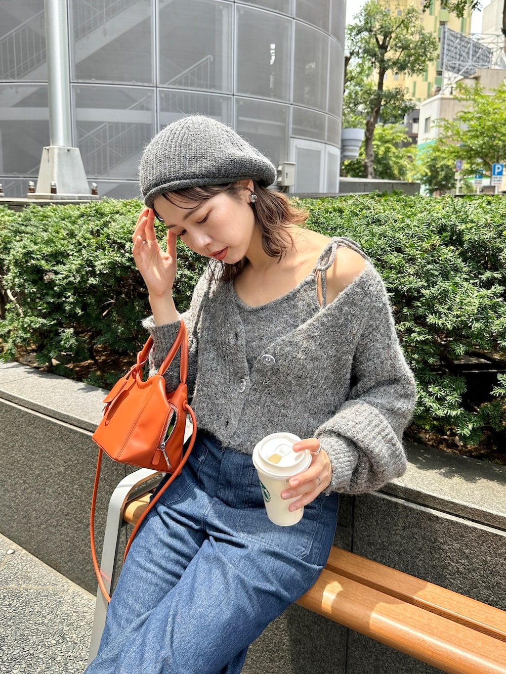 グレー系のトップス、オレンジ系のトートバッグ、ブルー系のデニムパンツを着用したレディースの夏コーディネートの4枚目の写真