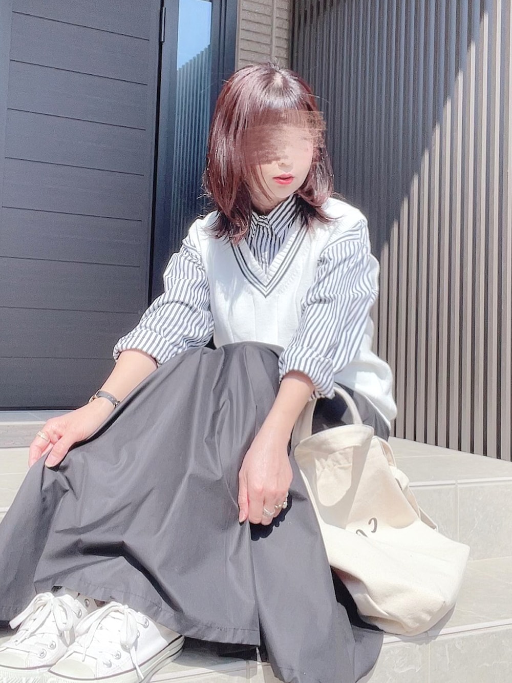 ホワイト系のベスト、ブルー系のシャツ/ブラウス、ブラック系のスカートを着用したレディースの春コーディネートの2枚目の写真