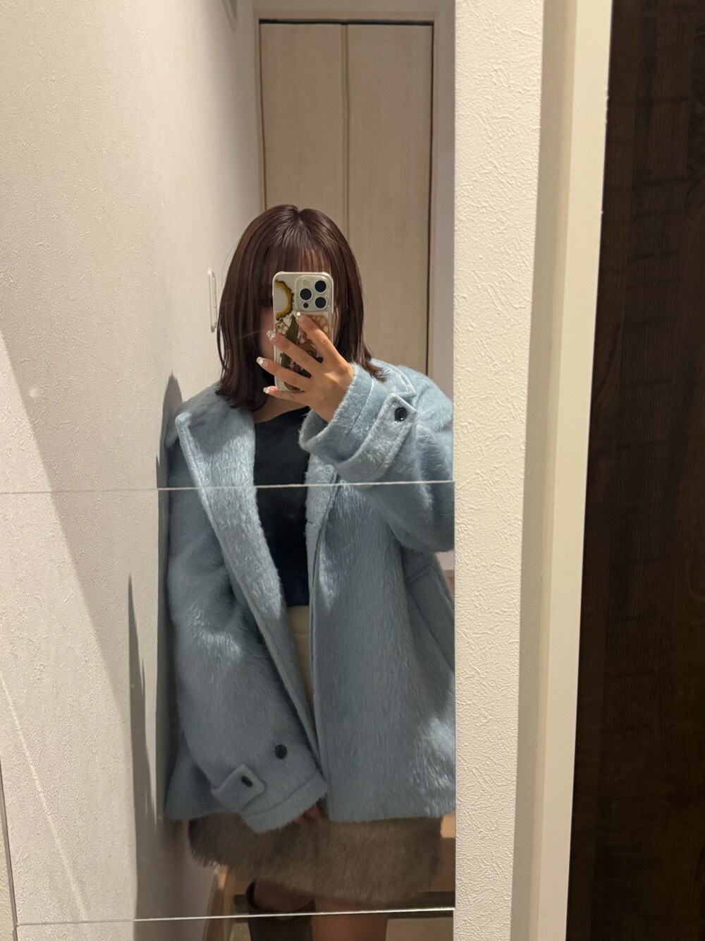 ブラック系のニット/セーター、ブルー系のステンカラーコート、ベージュ系のスカートを着用したレディースの冬コーディネートの2枚目の写真