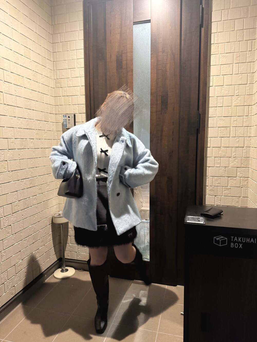 ホワイト系のニット/セーター、ブルー系のステンカラーコート、ブラック系のスカートを着用したレディースの冬コーディネートの2枚目の写真