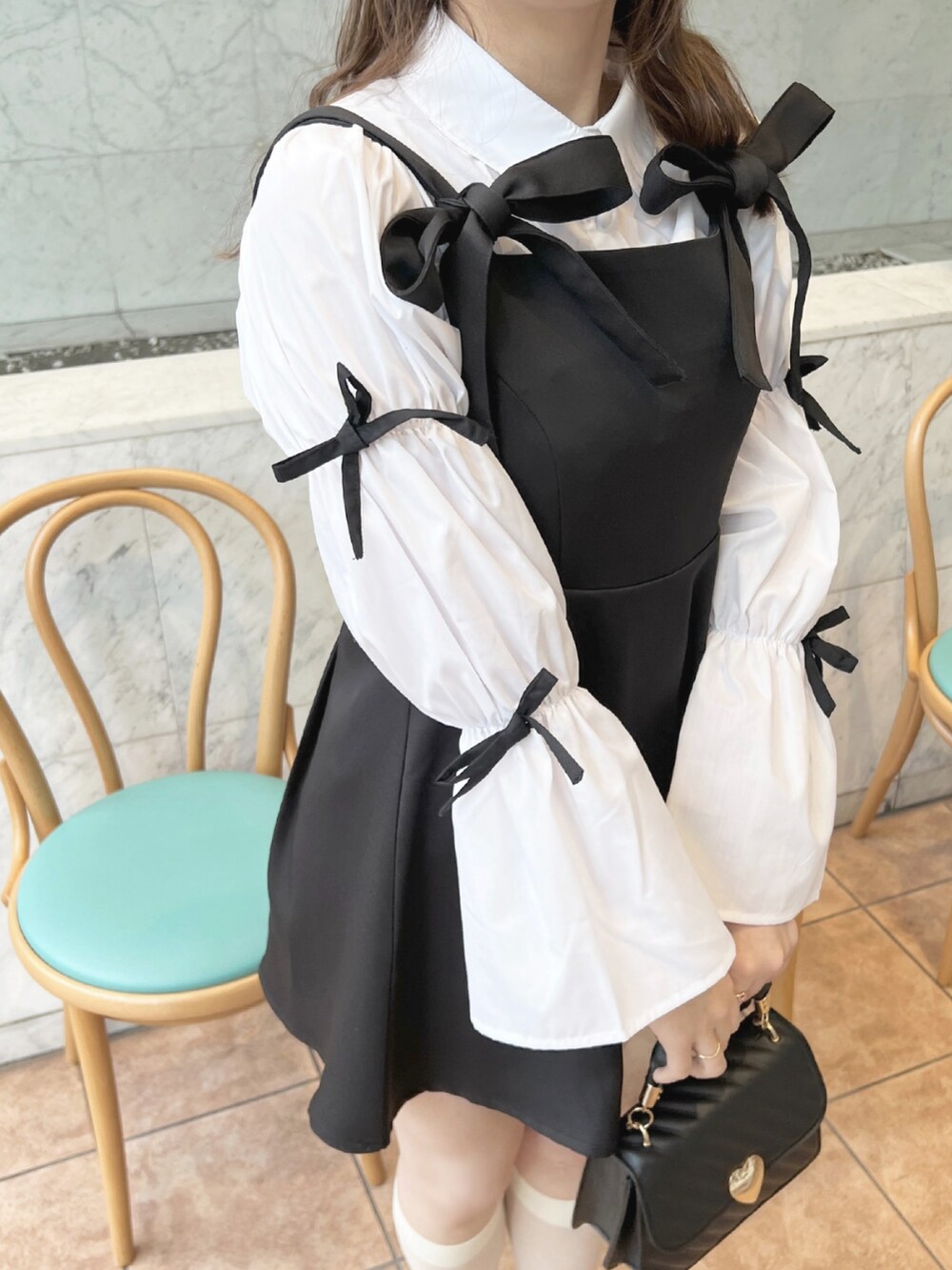 ブラック系のワンピース、ホワイト系のシャツ/ブラウス、ブラック系のパンプスを着用したレディースの春コーディネートの2枚目の写真