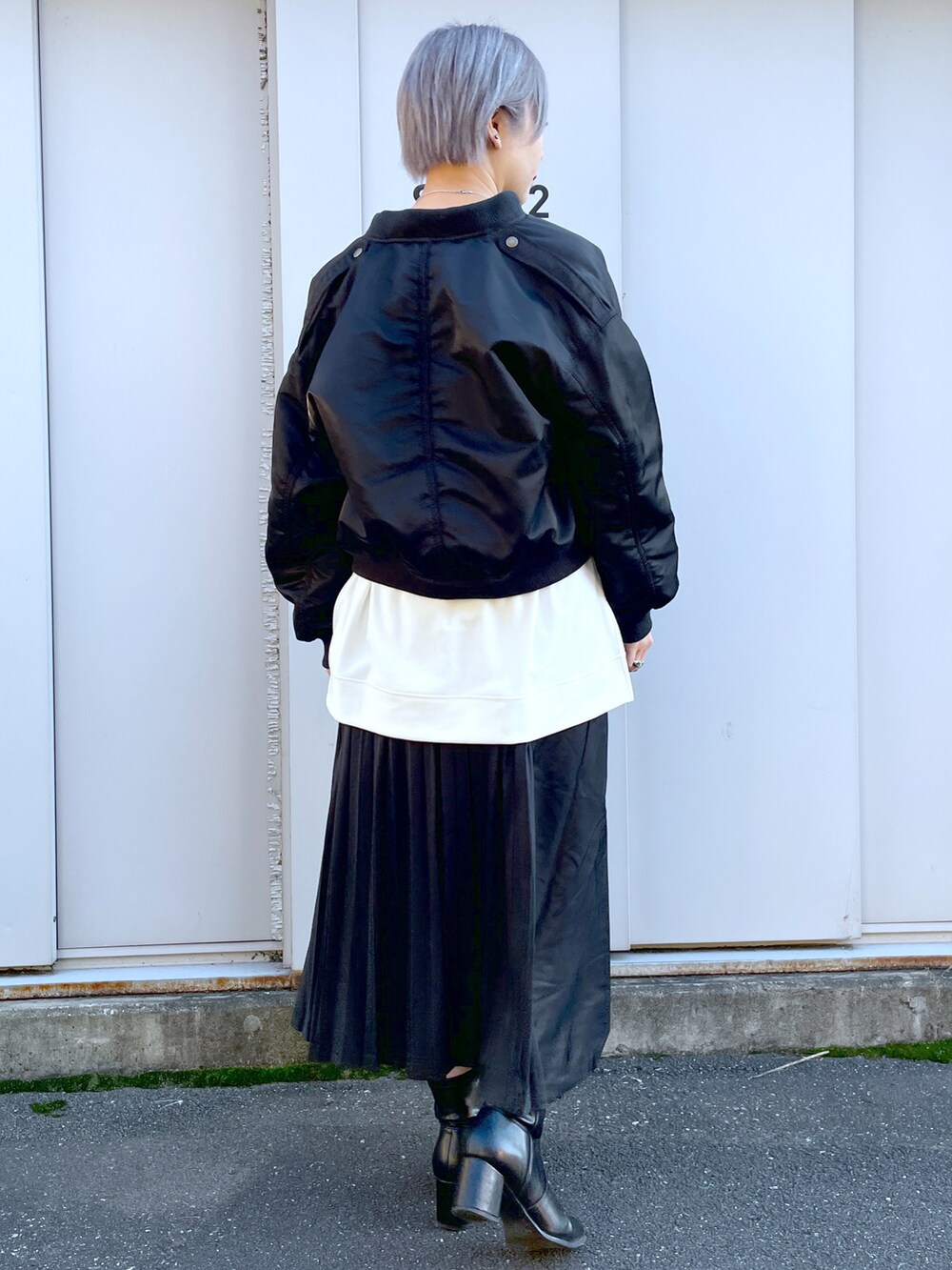 ブラック系のミリタリージャケット、ホワイト系のTシャツ/カットソー、ブラック系のスカートを着用したレディースの秋コーディネートの3枚目の写真