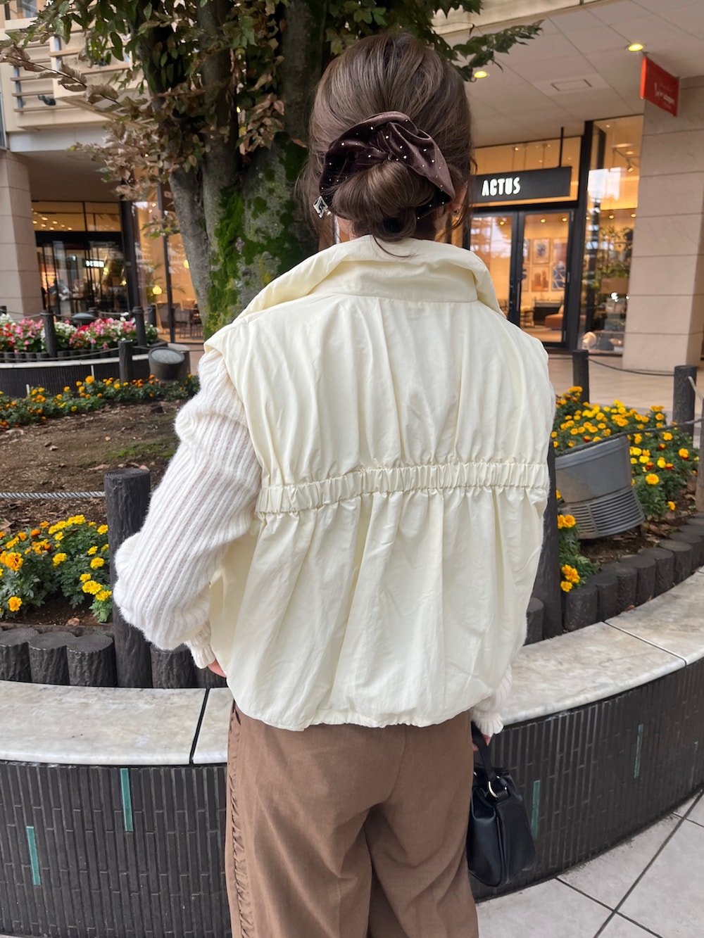 ブラウン系のその他パンツ、ブラック系のショルダーバッグ、ホワイト系のダウンベストを着用したレディースの秋コーディネートの4枚目の写真