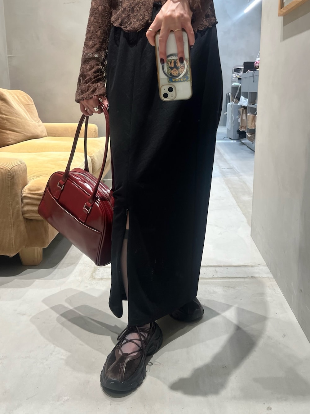 ブラック系のスカート、レッド系のボストンバッグ、ブラウン系のTシャツ/カットソーを着用したレディースの夏コーディネートの3枚目の写真