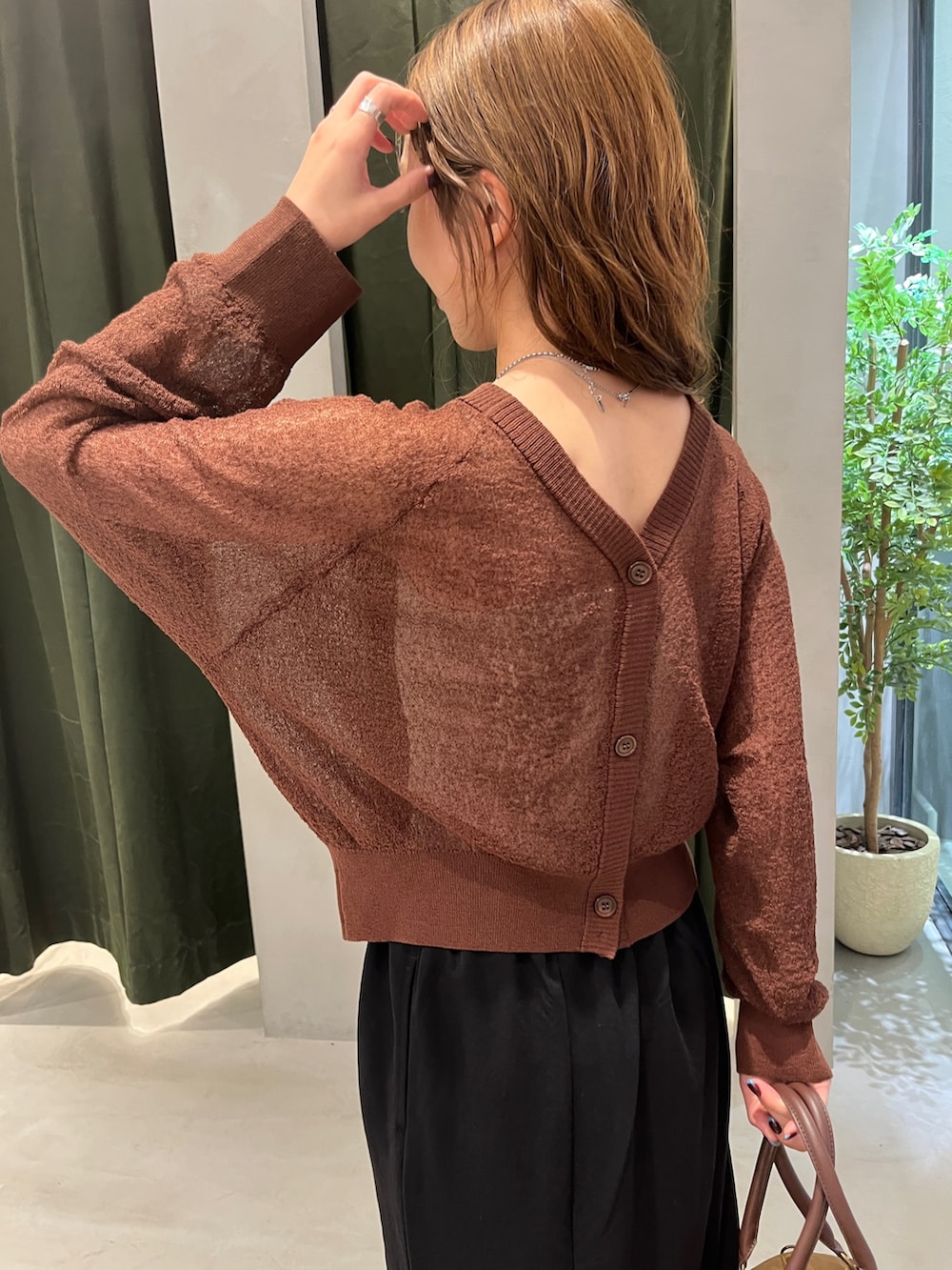 ブラック系のスカート、ブラウン系のカーディガン/ボレロ、ブラウン系のボストンバッグを着用したレディースの秋コーディネートの3枚目の写真