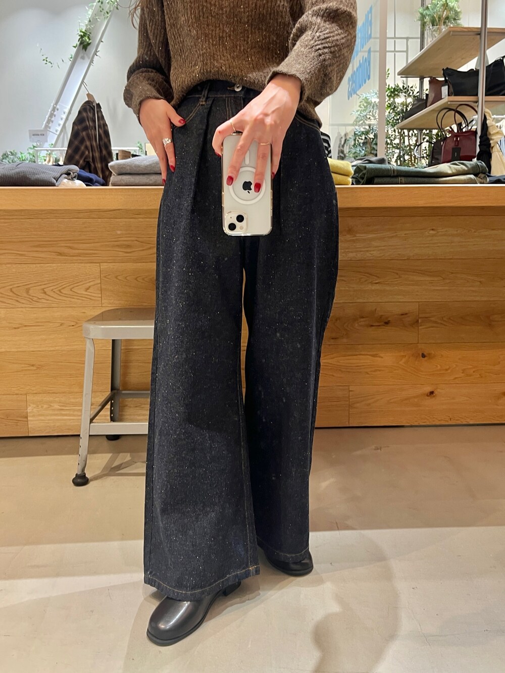 レッド系のショルダーバッグ、ブルー系のデニムパンツ、ブラウン系のニット/セーターを着用したレディースの秋コーディネートの3枚目の写真