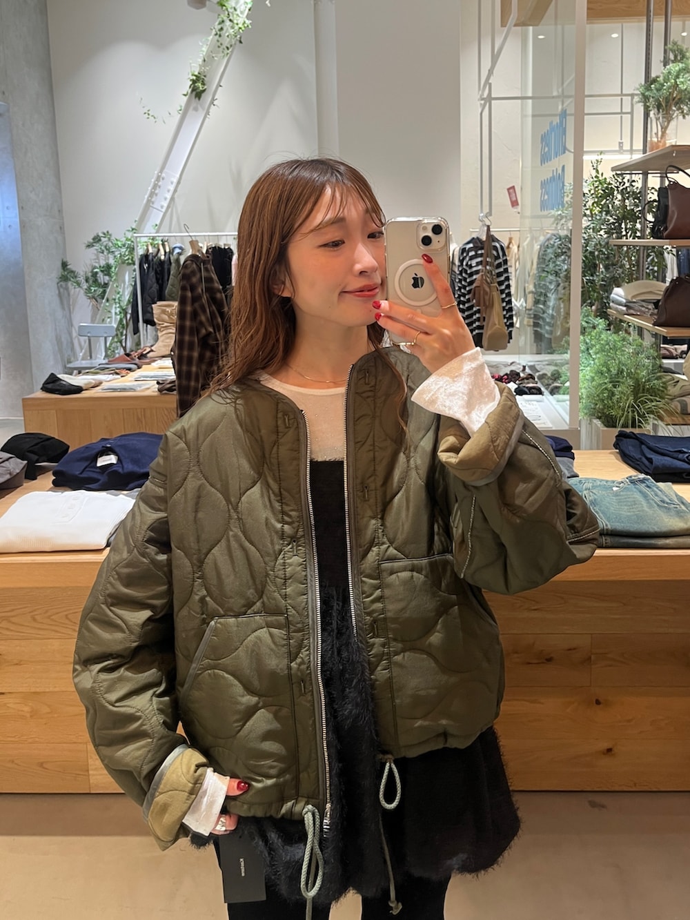 レッド系のボストンバッグ、グリーン系のブルゾン、ホワイト系のTシャツ/カットソーを着用したレディースの秋コーディネートの4枚目の写真