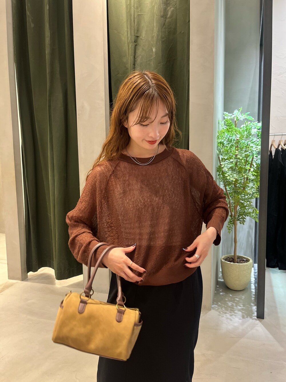 ブラック系のスカート、ブラウン系のカーディガン/ボレロ、ブラウン系のボストンバッグを着用したレディースの秋コーディネートの2枚目の写真