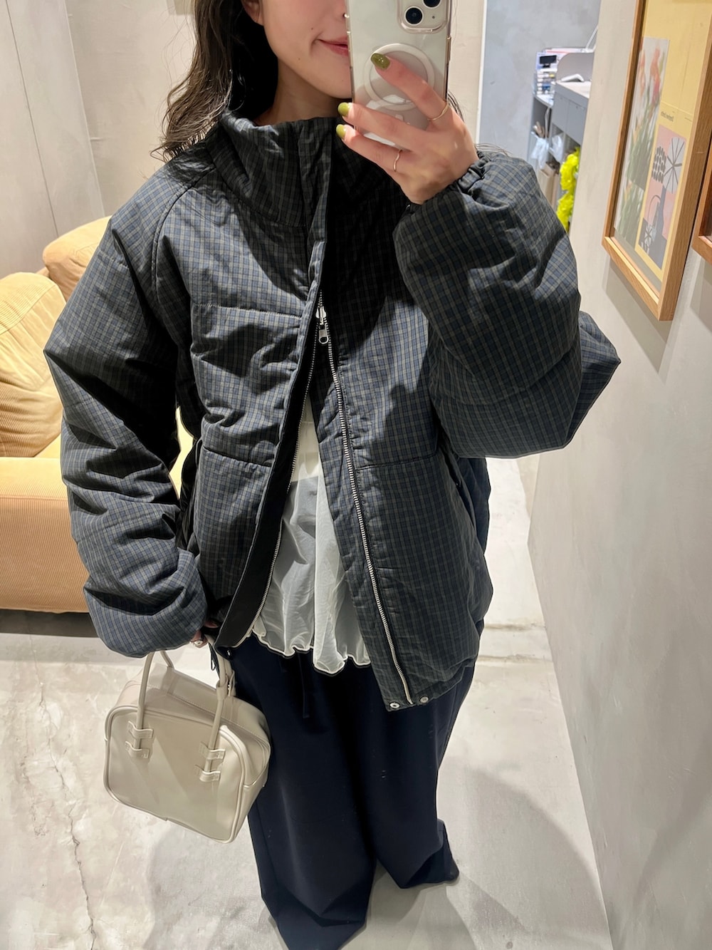 グリーン系のダウンジャケット/コート、ブルー系のスラックス、ホワイト系のハンドバッグを着用したレディースの秋コーディネートの2枚目の写真