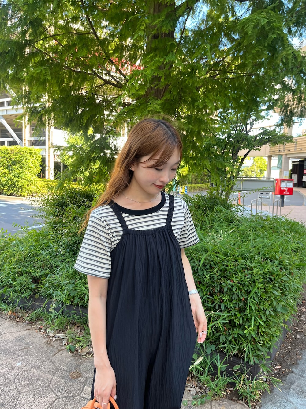 ホワイト系のTシャツ/カットソー、ブラック系のサロペット/オーバーオール、オレンジ系のボストンバッグを着用したレディースの夏コーディネートの2枚目の写真