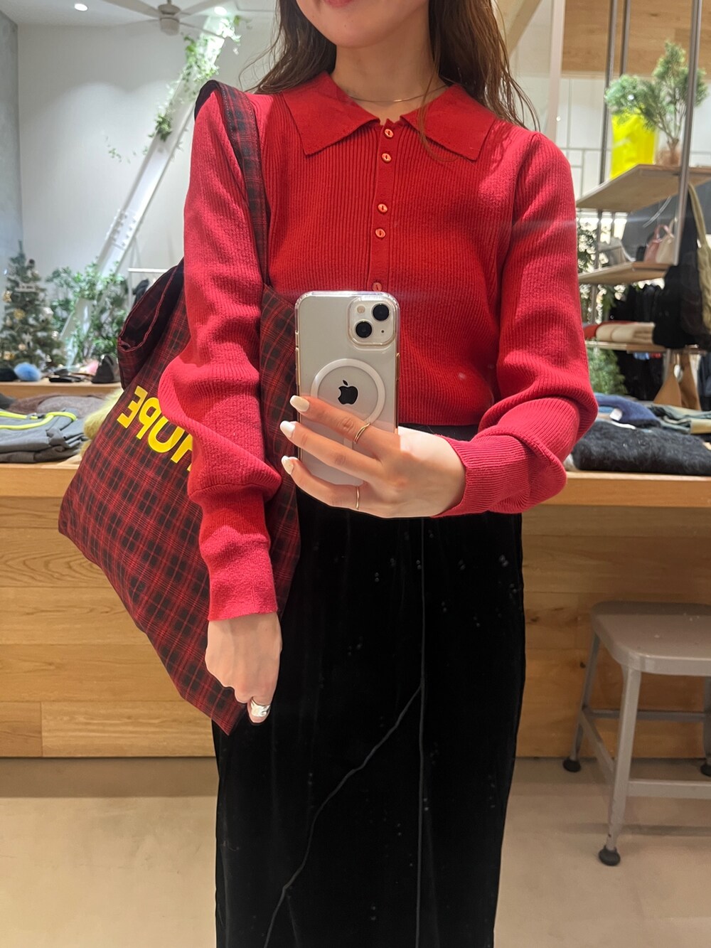 レッド系のニット/セーター、ブラック系のスカート、ブラック系のブーツを着用したレディースの冬コーディネートの2枚目の写真