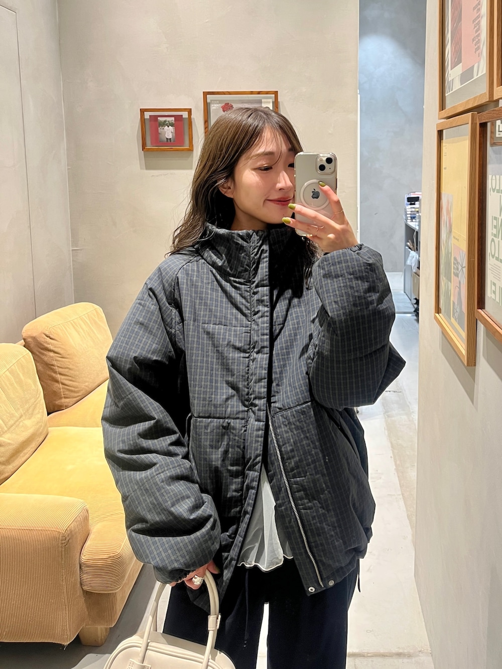 グリーン系のダウンジャケット/コート、ブルー系のスラックス、ホワイト系のハンドバッグを着用したレディースの秋コーディネートの3枚目の写真