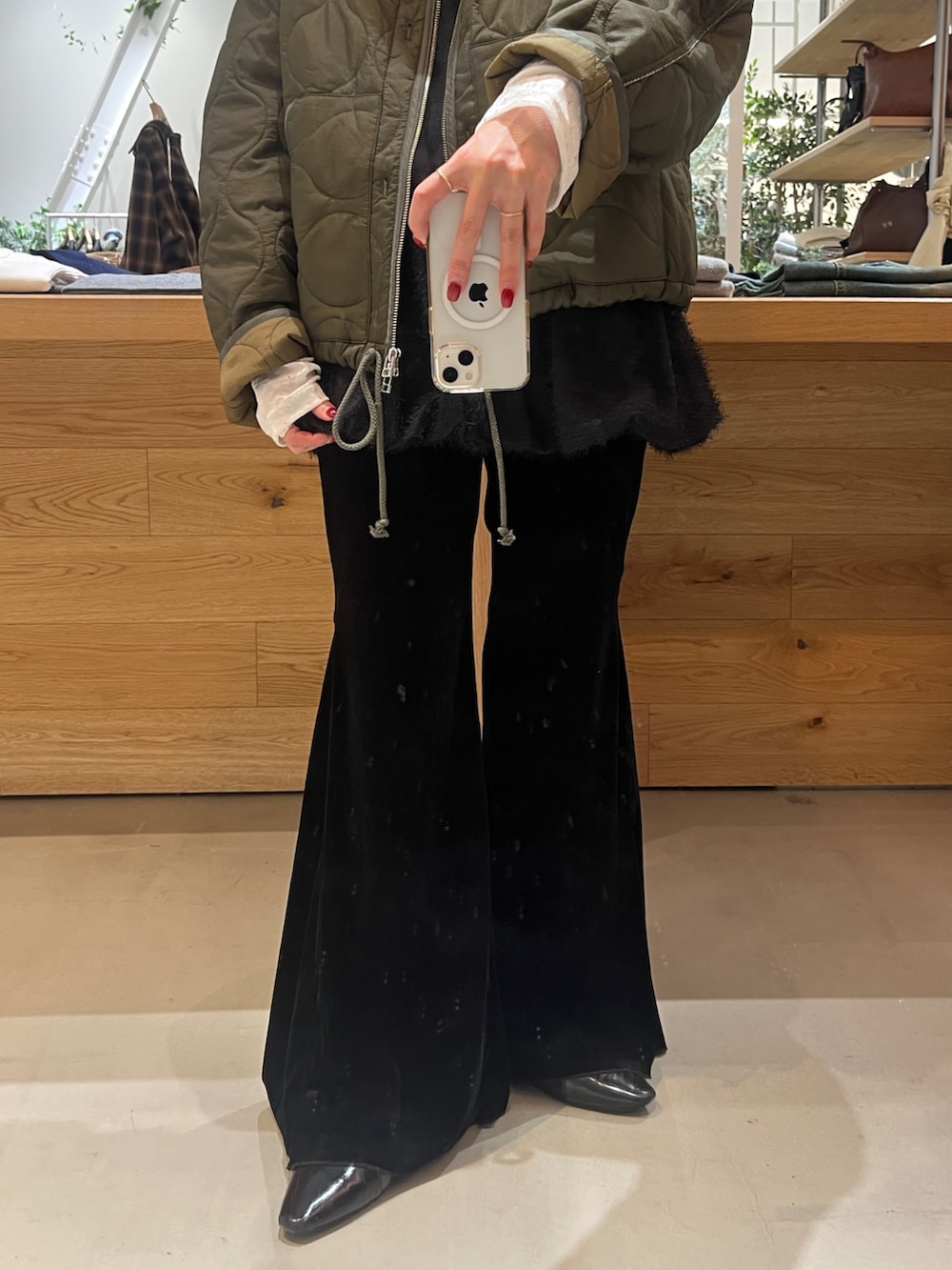 レッド系のボストンバッグ、グリーン系のブルゾン、ホワイト系のTシャツ/カットソーを着用したレディースの秋コーディネートの3枚目の写真