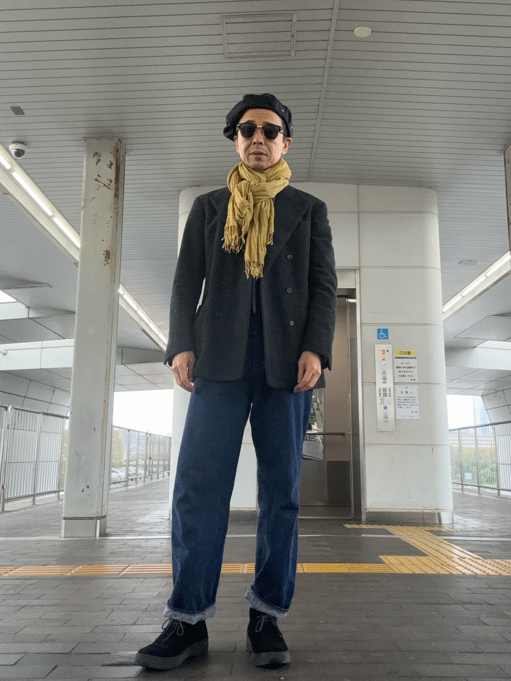 ブルー系のデニムパンツ、ブラック系のブーツ、グレー系のテーラードジャケットを着用したメンズの秋コーディネートの2枚目の写真