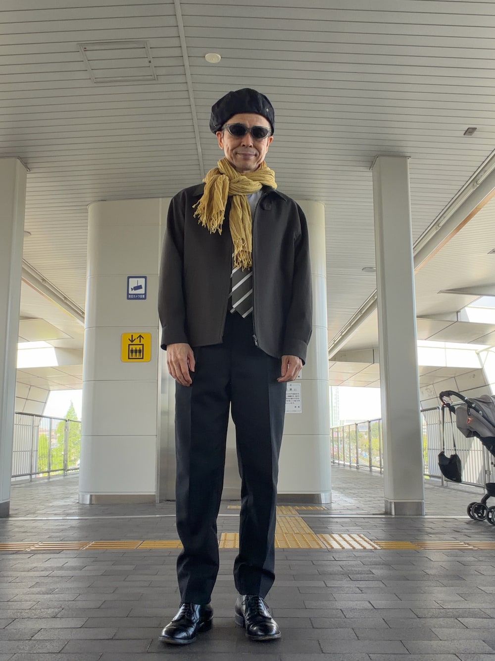 ブラック系のパンツ、ブラック系のドレスシューズ、グリーン系のブルゾンを着用したメンズの春コーディネートの2枚目の写真