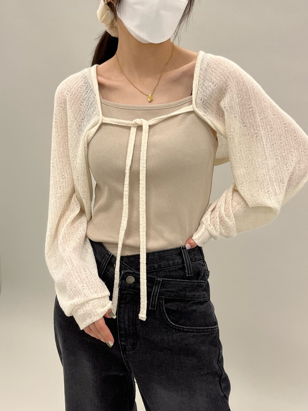 ベージュ系のカーディガン/ボレロ、ベージュ系のキャミソール、ブラック系のデニムパンツを着用したレディースの夏コーディネートの3枚目の写真