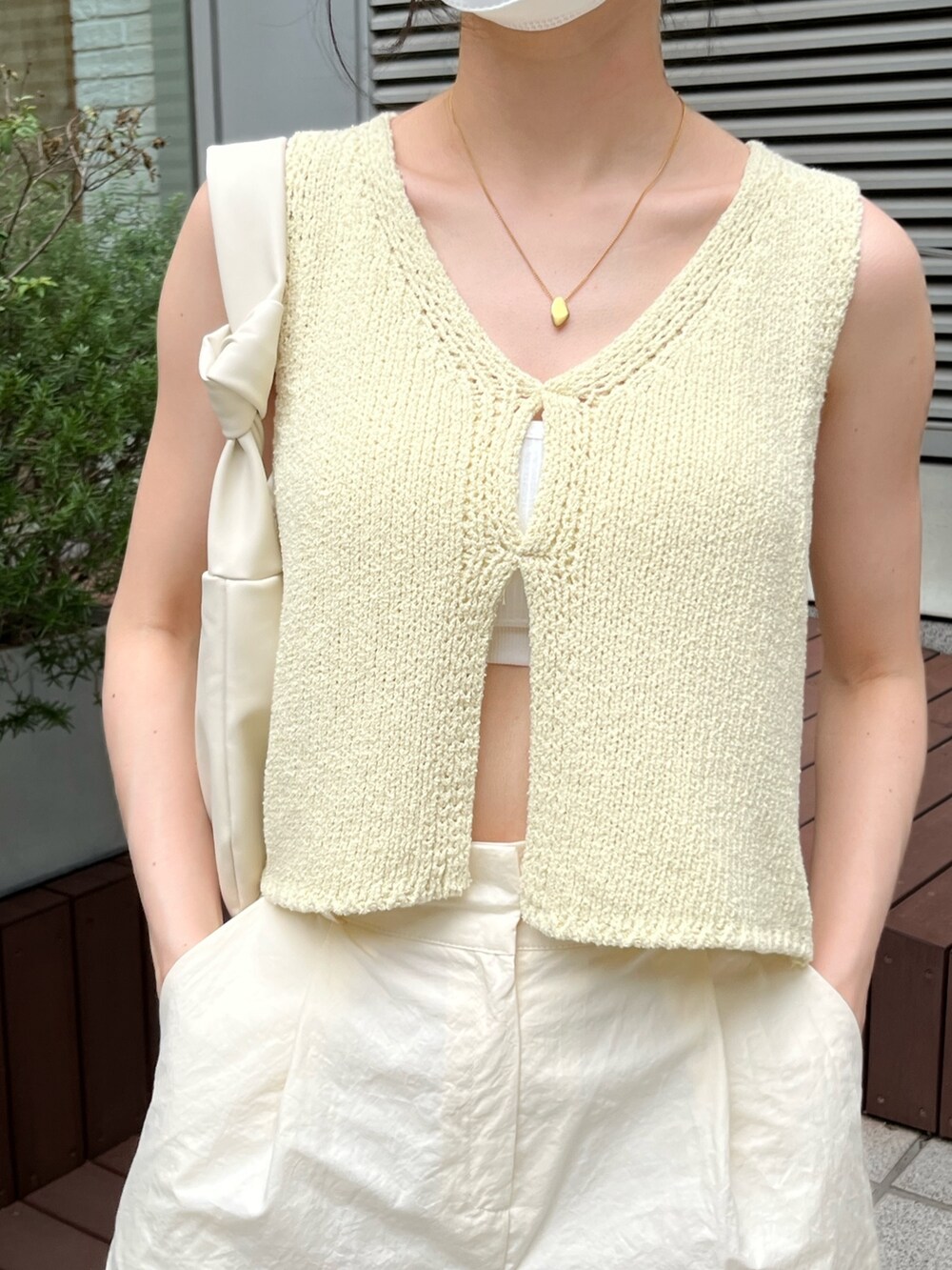 イエロー系のベスト、ベージュ系のその他パンツ、ベージュ系のローファーを着用したレディースの夏コーディネートの3枚目の写真